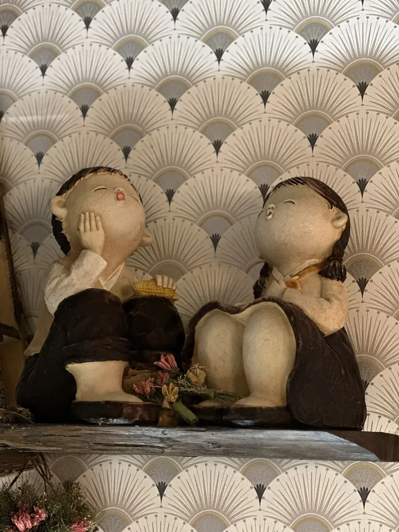 Figurines coréennes devant un mur à motif d’éventails